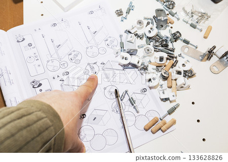 Hands craft puzzle, Individual configuring miniature wooden pegs on smooth surface, Detailed shot of hands organizing tiny wooden puzzle pieces on neutral background 133628826