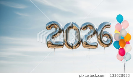 A festive display of silver 2026 balloons and a vibrant cluster of colorful balloons against a bright sky 133628933