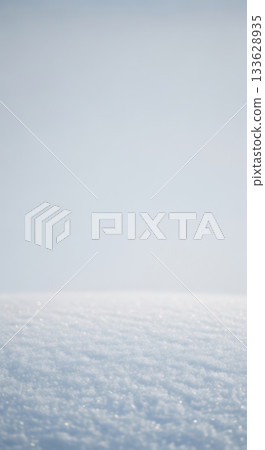 A pristine blanket of sparkling snow stretches to the horizon under a soft winter sky 133628935