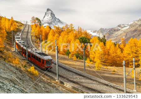 Red Train, Matterhorn Mountain and Golden Larches in Autumn. Switzerland Red Train, Matterhorn Mountain and Golden Larches in Autumn. Switzerland 133629543
