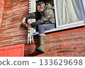 Linking power lines as installer attaches DC jack male to DC jack female during surveillance camera setup on rural home facade. 133629698