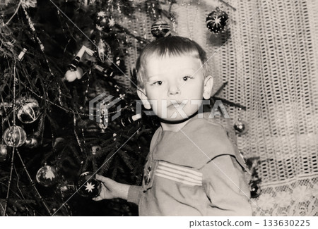 Vintage portrait of a little boy near a Christmas tree. Retro photo from 1970. Vintage portrait of a little boy near a Christmas tree. Retro photo from 1970. 133630225