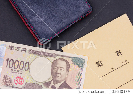 一個工資信封、幾張10000日元鈔票和一個皮質錢包放在黑色背景上。 133630329