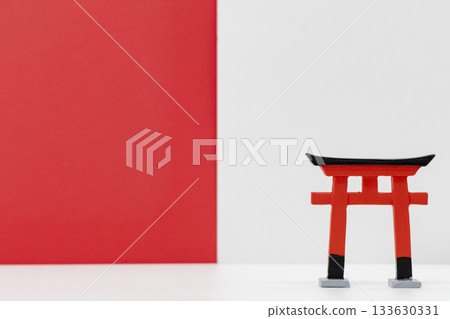 A miniature torii gate placed against a simple red and white background 133630331