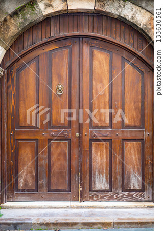 Rustic wooden double door with arched design in stone wall setting Rustic wooden double door with arched design in stone wall setting 133630561