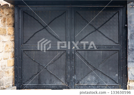 Rustic black metal gate with stone wall backdrop Rustic black metal gate with stone wall backdrop 133630596