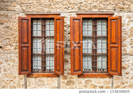 Rustic stone wall with wooden shuttered windows 133630605