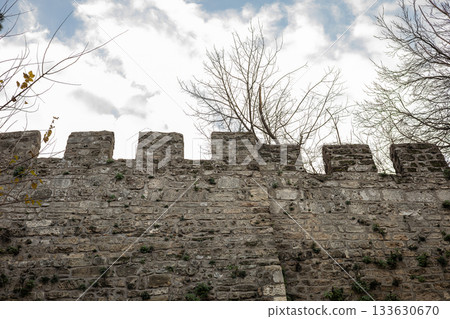 Medieval stone fortress wall with battlements under cloudy sky Medieval stone fortress wall with battlements under cloudy sky 133630670