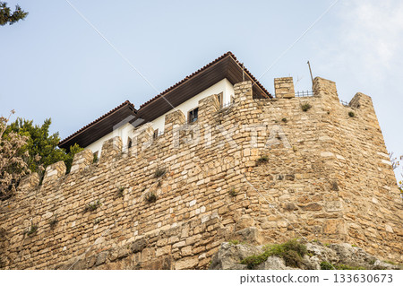 Historic stone fortress wall with rooftop structure under clear sky Historic stone fortress wall with rooftop structure under clear sky 133630673