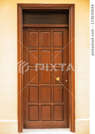 Wooden door with square panels and brass handle in brown frame Wooden door with square panels and brass handle in brown frame 133630684