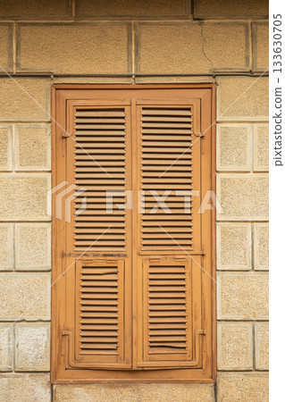 Rustic wooden shuttered window on stone building wall Rustic wooden shuttered window on stone building wall 133630705