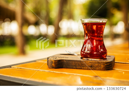 Steaming glass of turkish tea on wooden table in garden setting 133630724