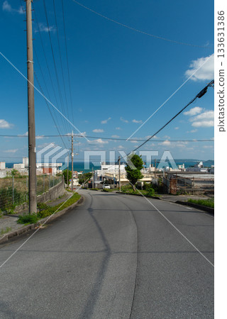 A clear sky, a cityscape with an emerald green sea, and a downhill slope 133631386