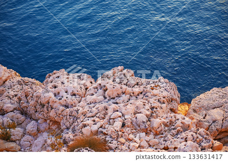 Rugged white rocks above deep blue sea 133631417