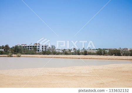 Desert landscape with lake with buildings and clear sky 133632132