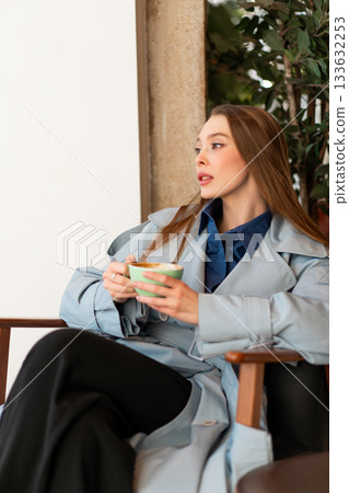 Young businesswoman in stylish coat holding coffee Young businesswoman in stylish coat holding coffee 133632253