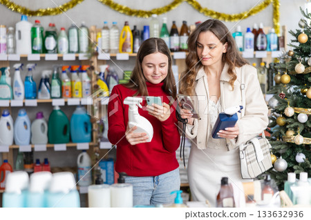 Woman with teen daughter scanning barcode on disinfectant spray in festive store 133632936
