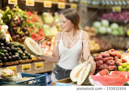 Young woman choosing a melon in a fruit store 133632938