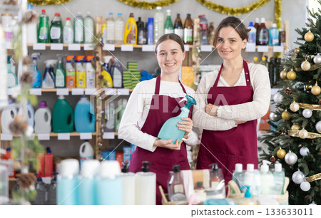 On New Years Eve, female store employee with teen girl helper in apron advertises household products 133633011