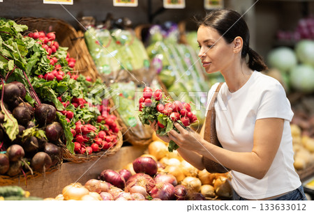 Adult woman choosing radishes at vegetable shop Adult woman choosing radishes at vegetable shop 133633012
