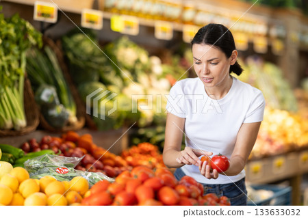 Adult woman choosing tomatoes at vegetable shop 133633032