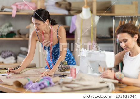Woman tailor draw dress pattern with curve ruler on paper, female master seamstress sewing Woman tailor draw dress pattern with curve ruler on paper, female master seamstress sewing 133633044