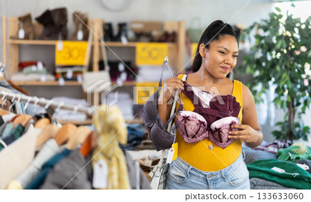Young woman chooses bra in fashionable clothing boutique Young woman chooses bra in fashionable clothing boutique 133633060