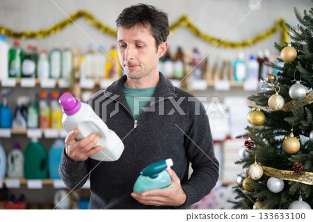 Man chooses spray glass cleaner and detergent in supermarket before Christmas 133633100