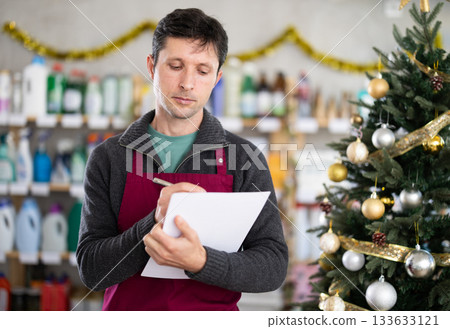 Adult man seller conducting inventory in decorated store Adult man seller conducting inventory in decorated store 133633121
