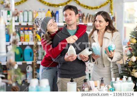 Couple man and woman with daughter choosing shampoo or shower gel in decorated store Couple man and woman with daughter choosing shampoo or shower gel in decorated store 133633124