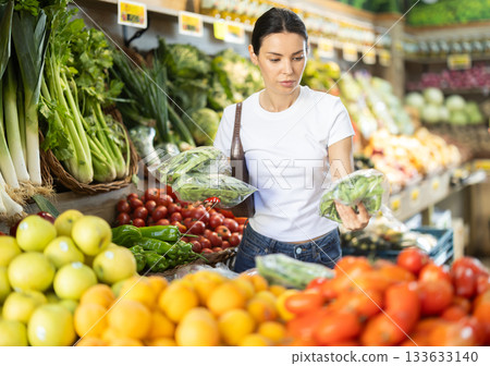 Adult woman chooses green onions at vegetable shop 133633140