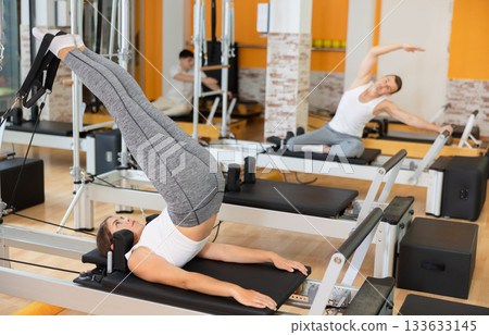 Girl performing reverse crunches with legs lift on Pilates reformer 133633145