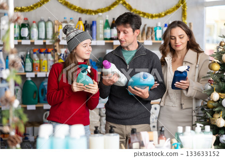 Couple man and woman with daughter choosing detergent and spray in decorated store 133633152