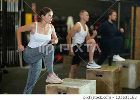 Focused girl stepping up on box during cross training at gym 133633168