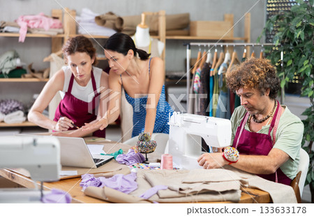 Female dressmaker and client review sketches on laptop Female dressmaker and client review sketches on laptop 133633178