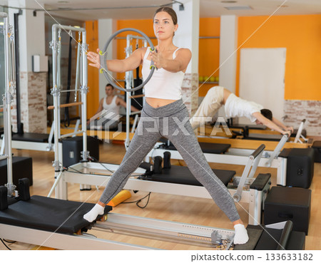 Girl doing exercises with flexible ring on Pilates reformer 133633182