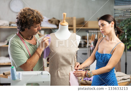 Female and male dressmakers working with mannequin Female and male dressmakers working with mannequin 133633213