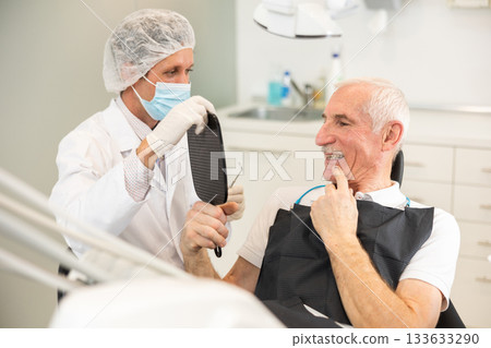 Adult male dentist showing result to male patient 133633290