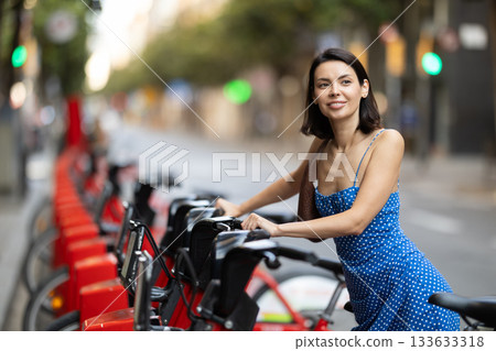 Young woman on rented bike on city street 133633318