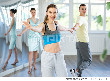 Couple in comfortable sports clothes learns boogie woogie dancing during individual lesson Couple in comfortable sports clothes learns boogie woogie dancing during individual lesson 133633391