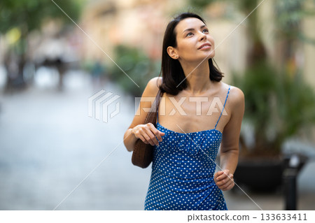 Young woman looks around on city street Young woman looks around on city street 133633411