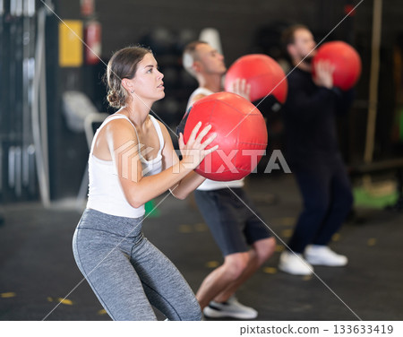 Girl performing intense cross workout with medicine ball 133633419