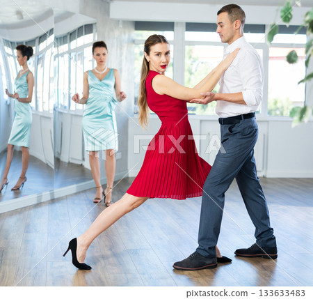 Couple in stage costumes learns waltz dancing during individual lesson 133633483