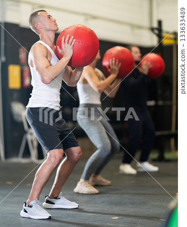 Sportive young guy working out with medicine ball in gym during crossfit workout 133633489