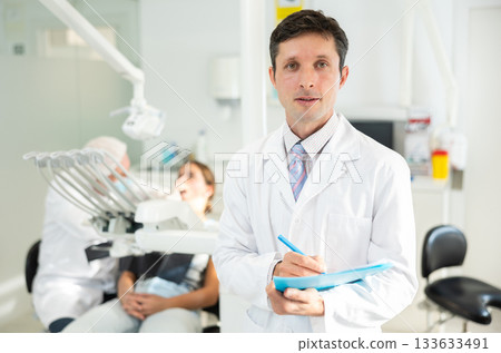 Adult male nurse taking notes in dental office Adult male nurse taking notes in dental office 133633491
