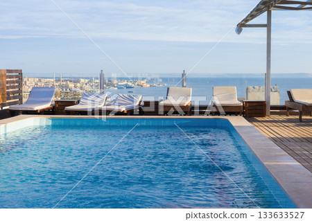 Rooftop pool overlooking cityscape and ocean horizon with loungers 133633527