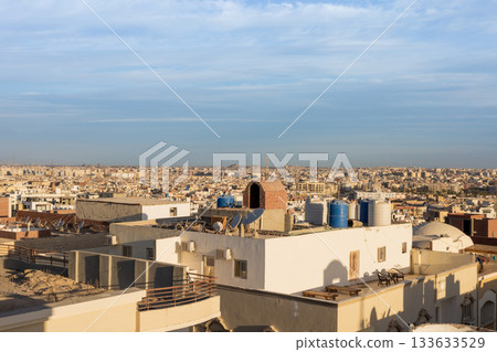 Urban rooftop scene overlooking expansive cityscape with blue sky and unique architecture 133633529