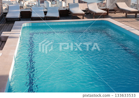 Rooftop pool with lounge chairs overlooking cityscape 133633533