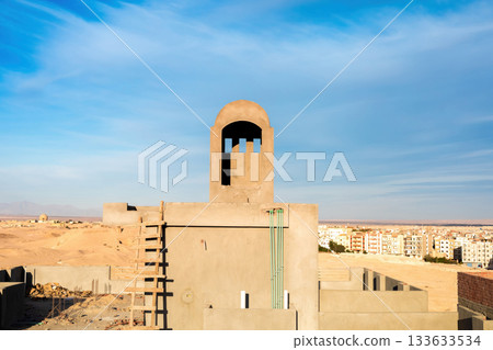 Desert landscape with traditional architecture and urban background under blue sky Desert landscape with traditional architecture and urban background under blue sky 133633534
