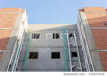 Urban construction scene with brick and concrete building facade against clear sky Urban construction scene with brick and concrete building facade against clear sky 133633540